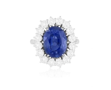 A SAPPHIRE AND DIAMOND CLUSTER RINGThe oval-shaped sapphire weighing approximately 5.30cts within a six-claw setting and bril