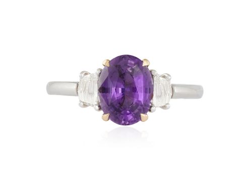 A SAPPHIRE AND DIAMOND DRESS RINGThe purple oval-shaped sapphire weighing 2.06cts within a four-claw setting and between two 