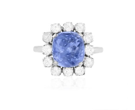 A SAPPHIRE AND DIAMOND CLUSTER RINGThe central cushion-shaped sapphire weighing approximately 4.50cts within a four-claw sett