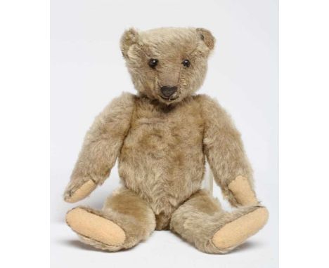 An old Steiff teddy bear, with black button eyes, sewn nose, replaced felt pads, light orange plush and ear button, 12" long 