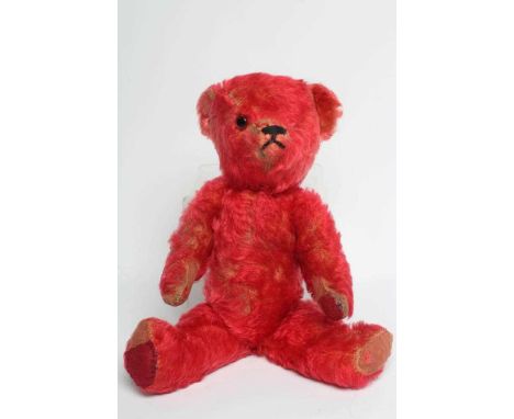 A rare pre-war red teddy bear, with one amber glass eye, sewn nose, red plush and red cloth pads, 16" long (Est. plus 24% pre