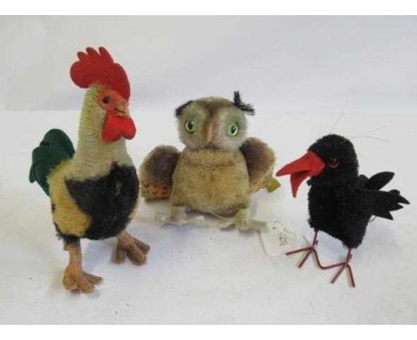 Three Steiff birds, comprising a Hahn with silver button on its tail, an owl with silver button and label and a Woll Rabe wit