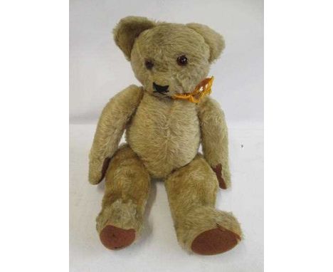 A pre-war English teddy bear, with glass amber eyes, later sewn nose, light orange plush and felt pads, 22" long (Est. plus 2