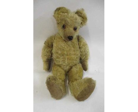 An old English teddy bear, with large amber glass eyes, shaved muzzle, sewn nose, yellow plush and cloth pads, 21 1/2" long (