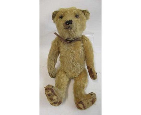 A German teddy bear, c.1910, with black shoe button eyes, sewn nose, blond plush and cloth pads, 14" long (Est. plus 24% prem