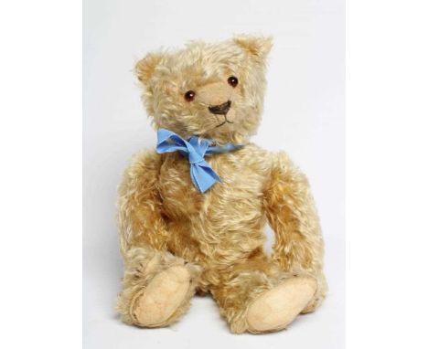 A pre-war teddy bear, with amber glass eyes, sewn nose, long orange plush and felt pads, 19 1/2" long (Est. plus 24% premium 