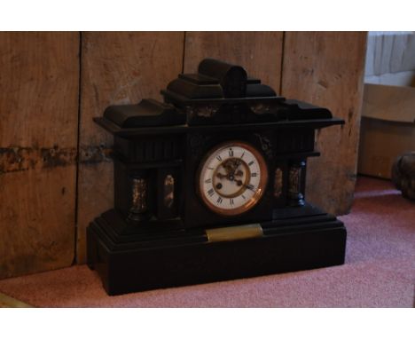 A Victorian eight day black slate mantel clock, with enamelled chapter ring with Roman numerals and movement striking on a go