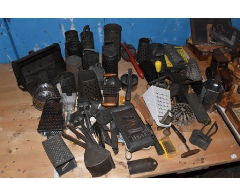 A large collection of assorted food graters through the ages, various ages, styles, and materials, with some herb choppers. P