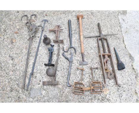 A collection of vintage wrought and cast iron agricultural tools and accessories, including two jacks, a pair of tractor peda