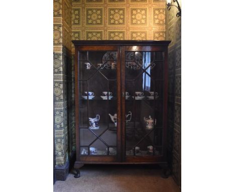 A 1920s oak display cabinet, with two astragal glazed doors enclosing glass shelves, on cabriole legs, height 138cm, width 97