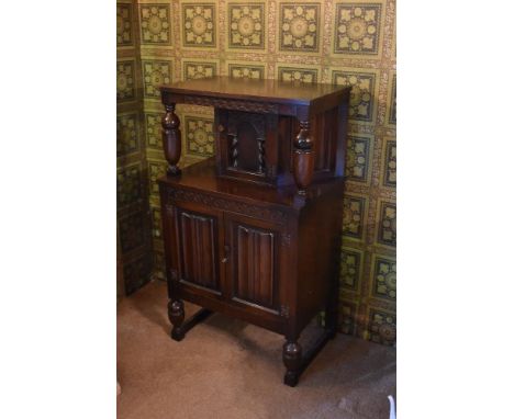 A 1940s carved and stained oak court cupboard, with arched panelled door above two linenfold carved panelled doors enclosing 