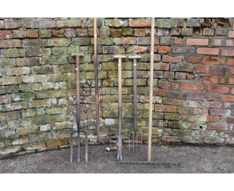A collection of five vintage, agricultural and garden tools, including a pikel, garden rake, a broad pronged fork, a smaller 
