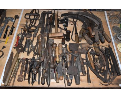 A large assortment of vintage carpentry and agricultural tools including two iron hooks, various hand scythes, chisels, etc.P