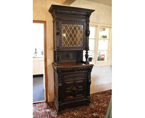 A late 19th century French carved and stained oak cabinet, the upper section with a replacement lead glazed door enclosing sh