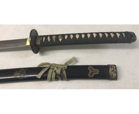 A modern oriental Samurai style sword with back fabric grip to handle. Black wooden scabbard with metal tip and carved devil 