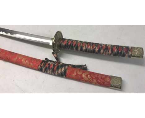 A modern oriental samurai style sword in scabbard with red and gold dragon design fabric cover. Black and white fabric grips 