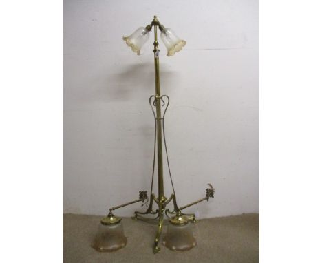 A Victorian brass standard lamp with later twin fittings and glass shades over a tubular column, on a scrolled, tripod base, 
