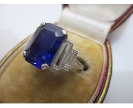 A white gold emerald cut Ceylon sapphire ring flanked by long baguette diamonds, total weight 4.75g, sapphire approximately 1