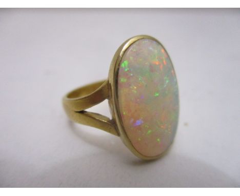 A 23ct gold ring, the oval opal set in a yellow metal surround