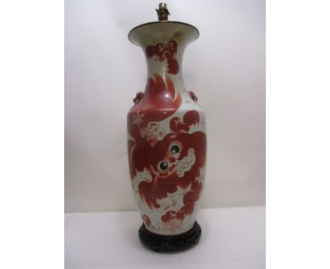 A late 19th century Japanese vase of ovoid form with a flared lip decorated in red, with dragon on a pierced, ebonized wooden