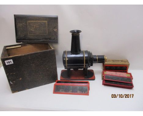 A German black and gold painted, tin plated magic lantern with a detachable funnel and lens with various slides to include ex