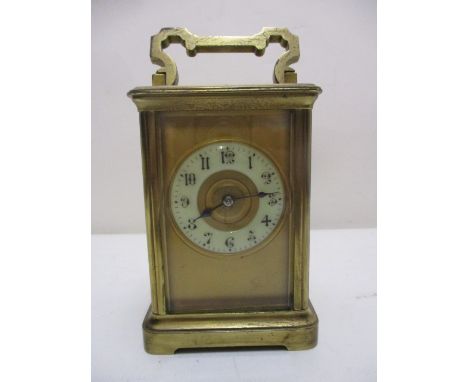 An early 20th century brass cased carriage clock having a folding top handle over glazed sides and brass door, with an enamel