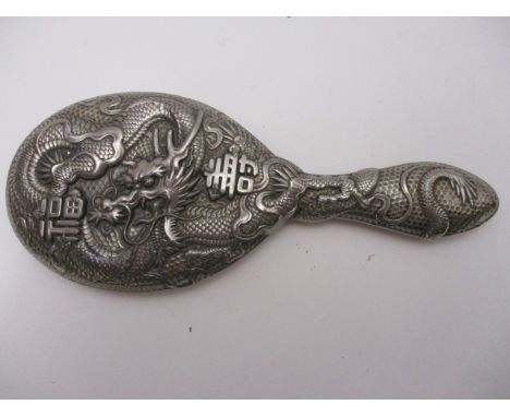An early 20th century white metal and foil backed hand mirror with deep embossed dragon and character decoration