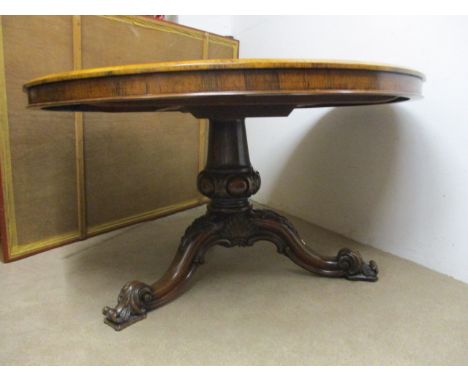 A mid Victorian rosewood dining table having a tip top, over a bolbous carved column, raised on a tripod base with acanthus c