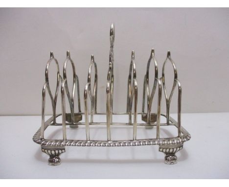 A George III silver toast rack by Rebecca Emes and Edward Barnard I London 1818, with a ring and foliate, scrolled handle and