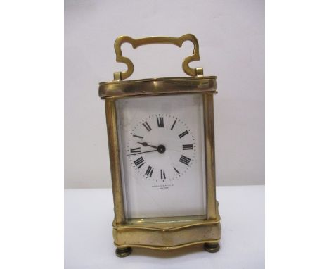 An early 20th century brass carriage clock, timepiece having a serpentine outline top with folding handle, over four glass pa