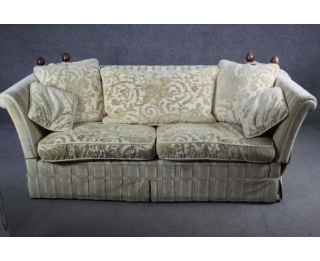 A two seater Knole sofa in cut floral brocade upholstery, drop arms with turned mahogany finials. 