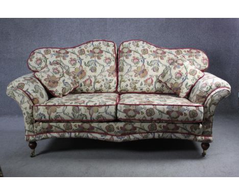 A 19th century two seater sofa in floral tapestry style upholstery on turned mahogany supports terminating in brass cup caste