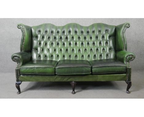 A Georgian style three seater wingback sofa in deep buttoned leather upholstery on cabriole supports. H.104 W.185 D.80cm 