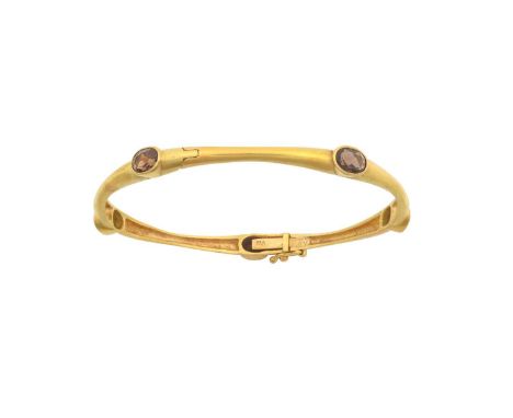 A Smoky Quartz Hinged Banglefive oval cut smoky quartz in yellow rubbed over settings interspaced by yellow tapered barsinner
