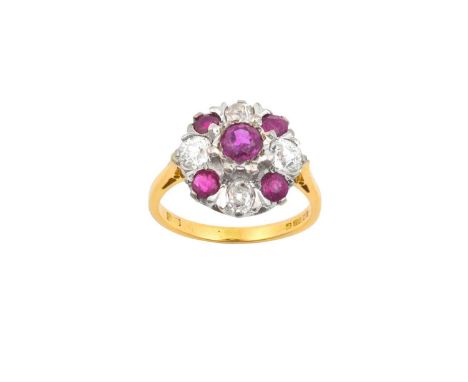 An 18 Carat Gold Ruby and Diamond Cluster Ringthe central raised round cut ruby within a border of alternating round cut rubi