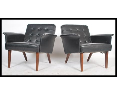 A pair of vintage danish influence mid 20th century, circa 1960's black faux leather armchairs. The chairs raised on splayed 