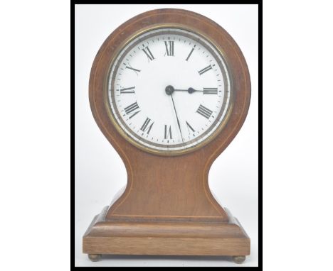 An early 20th century French mahogany inlaid balloon clock. Raised on a pedestal base with bun feet. The clock having a white