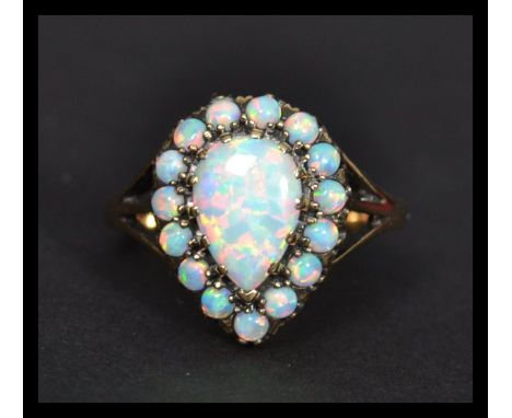 A 9ct gold pear shaped opal cluster ring the central stone having a halo of opals. Weighs 3.3 grams size Q.