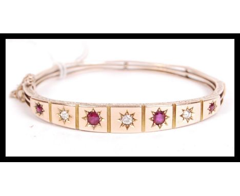 A 19th century Victorian 15ct gold diamond and ruby bangle bracelet being set with three old cut diamonds and four alternatin