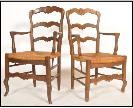 A pair of French country oak provincial windsor carver armchairs having rattan weave seats raised on block and turned legs wi