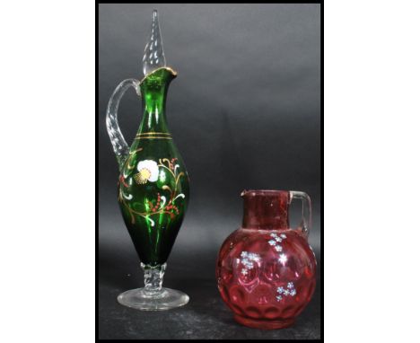 A 19th century cranberry glass jug handpainted overlay of flowers together with a green glass bohemian decanter with similar 
