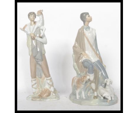 A Lladro ceramic figure group of a man holding a child, stamped to the base with impressed marks together with another simila
