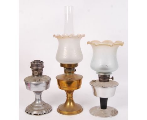 A  collection of three vintage 20th century oil lamps to include both brass and chrome examples, two with glass shades.