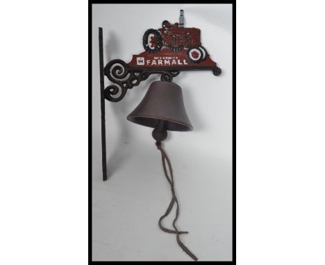 A vintage cast iron wall mounted bell in the form of a Farmall tractor. Measures 36 cm high.