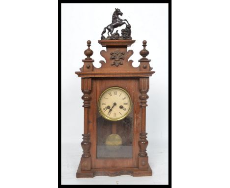 An early 20th century oak cased mantel clock having turned columns and carved applied decoration. The white enamel face havin