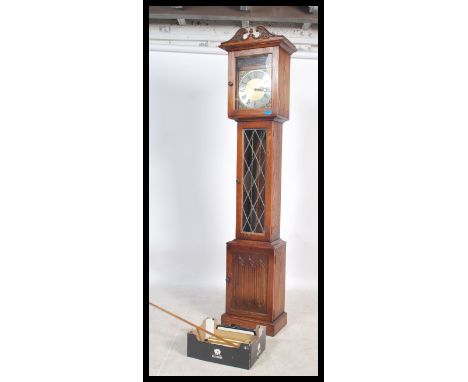 A 20th century antique style oak longcase grandfather clock with brass face and roman numeral chapter ring. The trunk with le