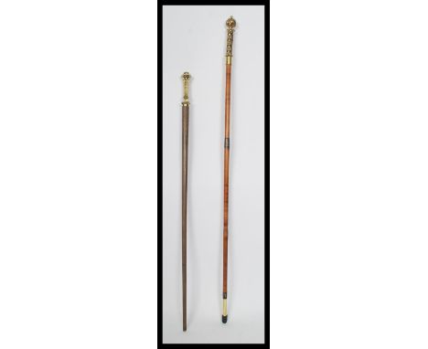 Two vintage 20th century walking stick canes having tapering shaft with ornate decorative gilt brass handles.