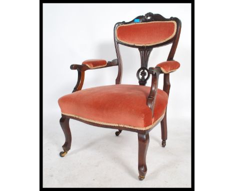 A 19th century Victorian inlaid and carved elbow mahogany salon arm chair raised on turned legs on ceramic castors, over stuf