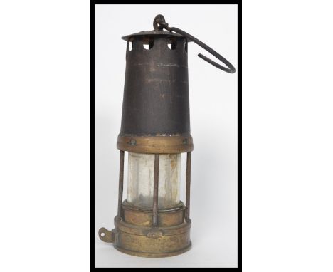 An early 20th century cast metal and brass miners lamp having a hook atop. Measures 26 cm high