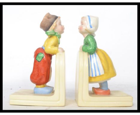 A pair of vintage mid 20th century ceramic bookend of a boy and girl in the manner of Hummel stamped to the base Foreign. Mea